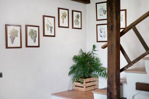 Una escalera con barandilla de madera y una pared decorada con ilustraciones botánicas enmarcadas.
