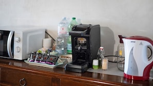 Una kitchenette con microondas, cafetera y hervidor sobre la encimera.