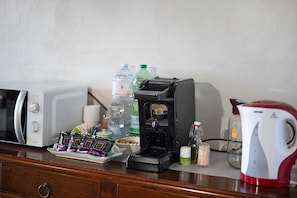 Una kitchenette con microondas, cafetera y hervidor sobre la encimera.