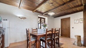 A dining area with a wooden table and chairs, a white refrigerator, and a wooden door. - Room 'Among the Olive Trees and the View' with Mountain Views, Private Garden, and Wi-Fi (Orvieto)