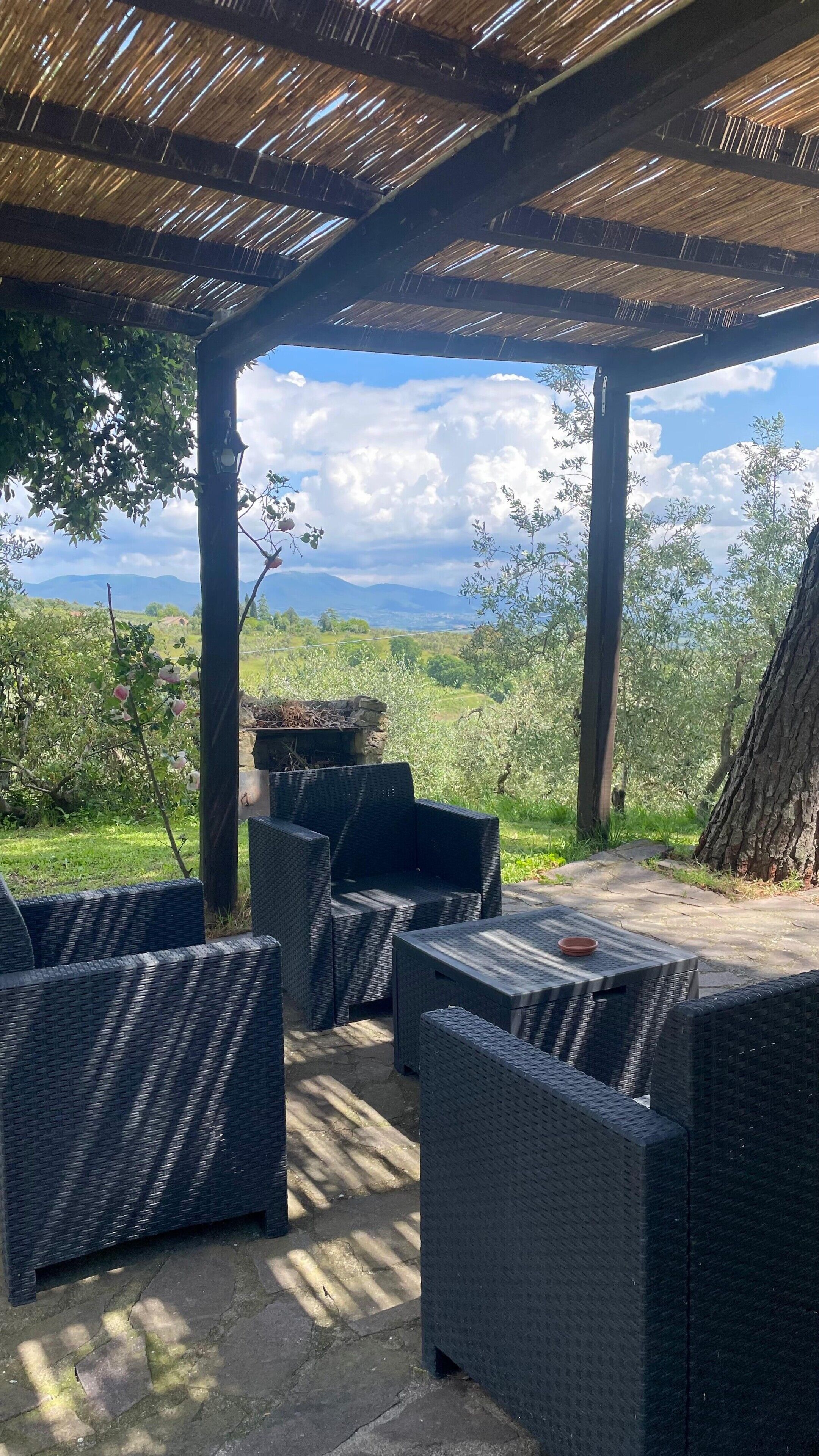 An outdoor patio area with wicker furniture and a view of the countryside.