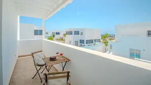 A balcony with a table, chairs, and a view of modern buildings and a clear sky. - Vacation Home 'Leize Con Piscina' with Sea View, Wi-Fi and Air Conditioning (Yaiza)