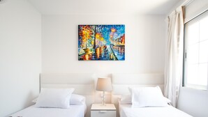 A hotel room with two beds, a nightstand with a lamp, and a painting on the wall. - Vacation Home 'Leize Con Piscina' with Sea View, Wi-Fi and Air Conditioning (Yaiza)