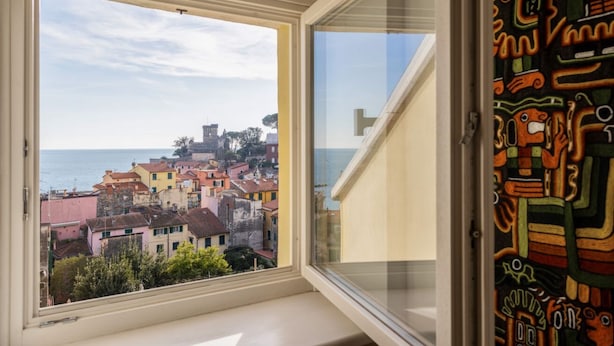 A window with a view of colorful buildings and a body of water. - The Abode of the Poets, TerreMarine (Lerici)