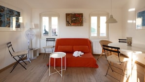 A bright living room with a red sofa, white chairs, a small round table, and a fan. - The Abode of the Poets, TerreMarine (Lerici)