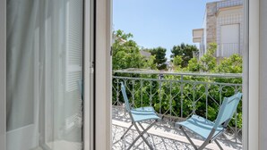 A balcony with two blue chairs, a metal railing, and a view of buildings and trees. - Apartment 'Marittima' with Balcony, Wi-Fi and Air Conditioning (Torre Canne)