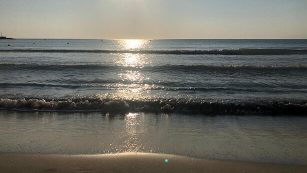 A beach with sunlight reflecting on the water and sand. - Apartment 'Marittima' with Balcony, Wi-Fi and Air Conditioning (Torre Canne)