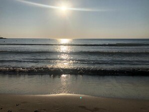 Une plage où la lumière du soleil se reflète sur l’eau et le sable.