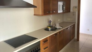 A kitchen with wooden cabinets, a stainless steel sink, a built-in oven, and a stove.