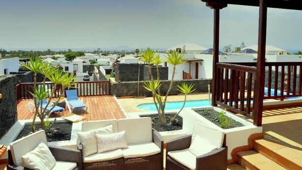 A rooftop terrace with a pool, outdoor seating, and a view of the surrounding buildings.