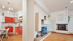 A modern kitchen with red cabinets, a built-in TV, and a fireplace.