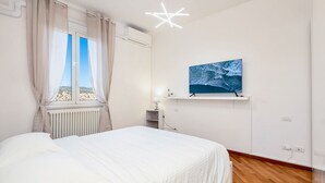 A bedroom with a bed, a window with curtains, a wall-mounted TV, and a star-shaped light fixture.