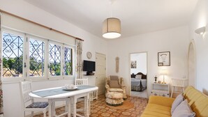 A room with a dining table, chairs, a sofa, a television, and a patterned floor.