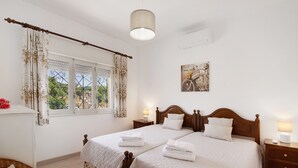 A double bed with a wooden headboard, a bedside table with a lamp, and a window with curtains.