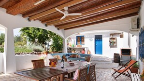 An outdoor patio with wooden furniture, a ceiling fan, and a view of the garden.