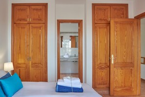 A bedroom with a bed, a nightstand, a lamp, and wooden wardrobes.