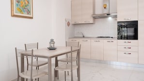 Una cocina moderna con armarios de colores claros, una campana extractora de acero inoxidable y un horno negro.