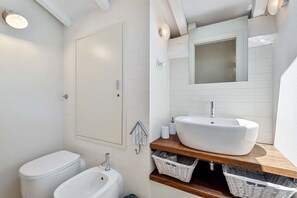 A bathroom with a toilet, bidet, and a sink with a mirror above. There are baskets under the sink and a towel rack on the wall. - The Charme is the perfect apartment for your holidays with family and friends.Elegance, refinement and quality are the characteristics of this house located in the center of La Spezia. This beautiful apartment is placed in a pedestrian area in the best n (La Spezia)