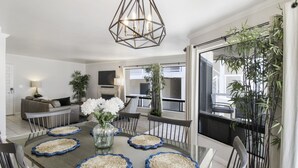 Un comedor con una mesa redonda, sillas y un jarrón central con flores.