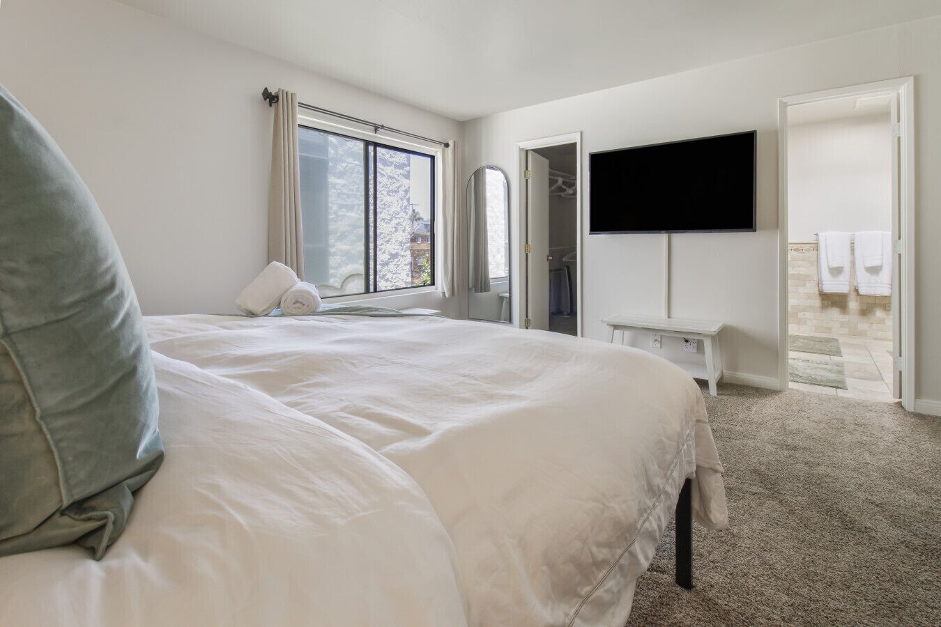 Ein Hotelzimmer mit einem großen Bett, einem flachbildfernseher an der Wand, einem begehbaren Kleiderschrank und einem Badezimmer mit Dusche und Handtüchern.