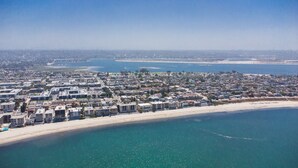 Vista aérea de una ciudad costera con una extensa playa, edificios residenciales densos y un mar azul cristalino.