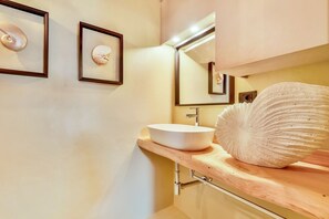 Un baño con tocador de madera, un lavabo blanco y una gran concha decorativa.