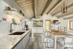 Uma cozinha moderna com uma ilha grande, armários brancos e teto de madeira.
