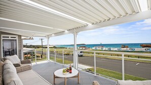 A covered outdoor seating area with a view of the beach and ocean.