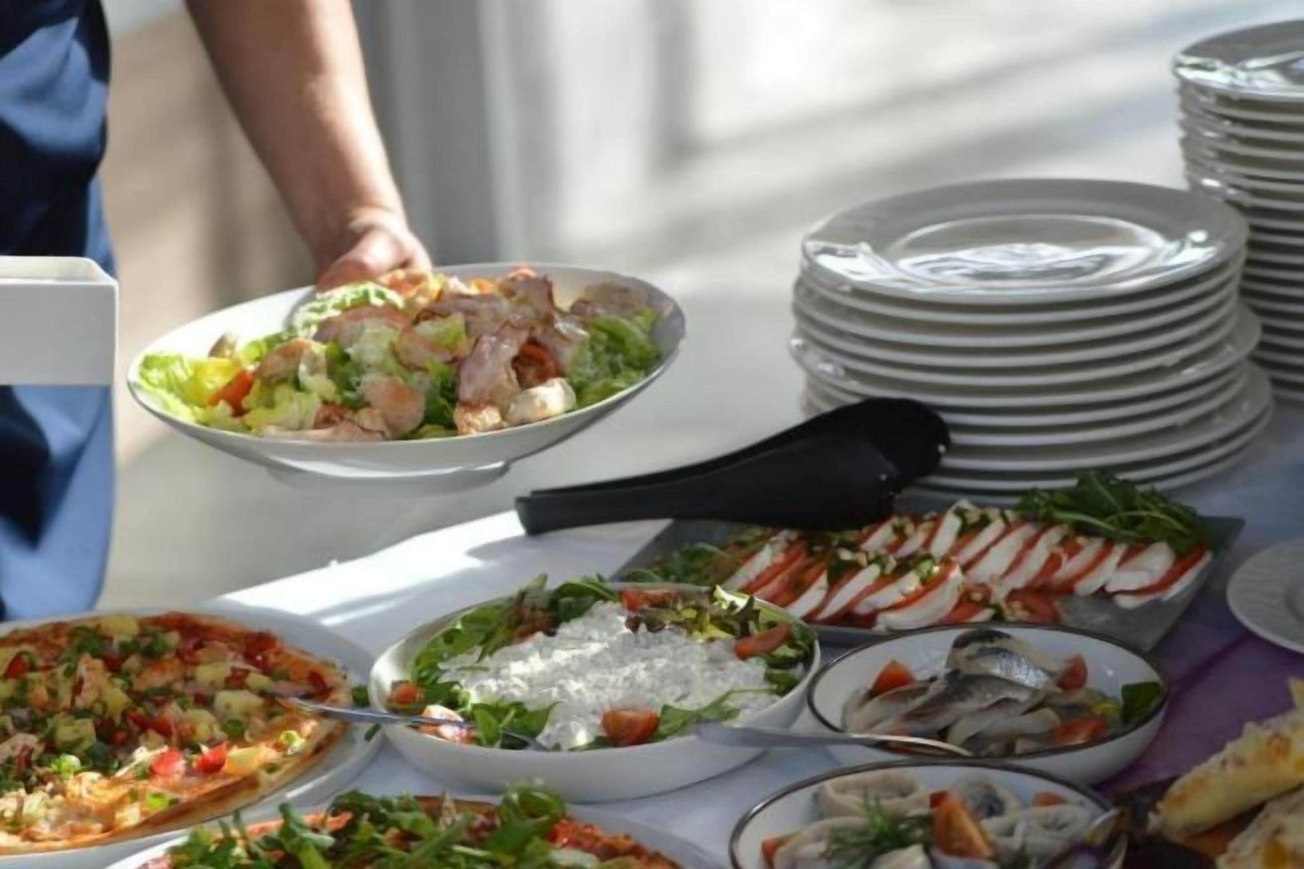 Een buffettafel met diverse gerechten, waaronder zeevruchten, salades en pizza's.