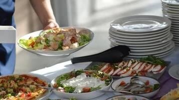 Een buffettafel met diverse gerechten, waaronder zeevruchten, salades en pizza's.