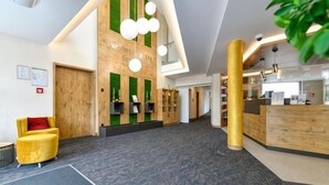 Un hall d’entrée moderne avec un comptoir d’accueil, un fauteuil jaune et un espace d’accueil en bois.