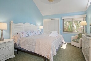 Une chambre à coucher comprenant un lit, des tables de chevet, une chaise et une commode.
