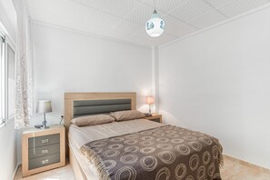 Une chambre à coucher comprenant un lit, des tables de chevet, une lampe et un luminaire au plafond.