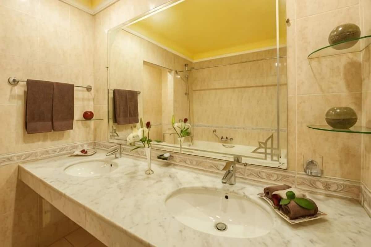 Une salle de bain avec deux lavabos, un grand miroir et des objets décoratifs.