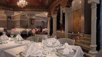 An elegantly set dining area with tables, candles, and a chandelier.