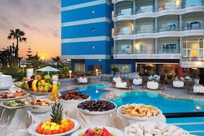 A poolside buffet with various food items and a pool in the background. - Val D Anfa Casablanca (Casablanca)