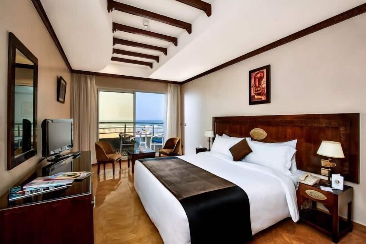 Une chambre d’hôtel dotée d’un grand lit, d’une télévision, d’un bureau avec une chaise, d’un balcon avec vue et d’un plafond en bois.