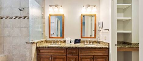 Un baño con lavamanos doble, zona de ducha y vestidor.