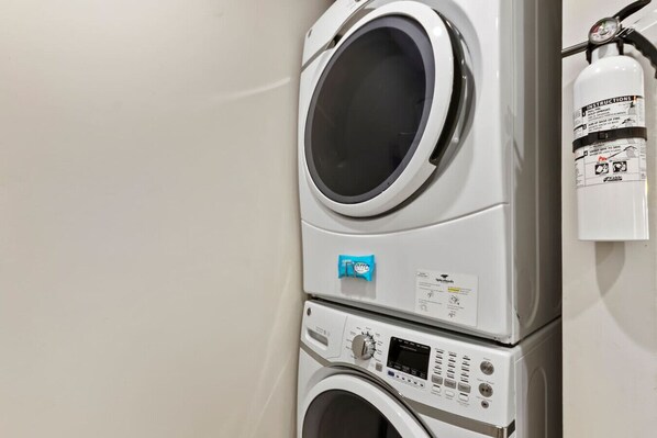 A stacked washer and dryer unit with a control panel and a fire extinguisher mounted on the wall. - 578 - Steps to Beach, Sleeps 6, 2 BD, 2 BA (Hilton Head Island)