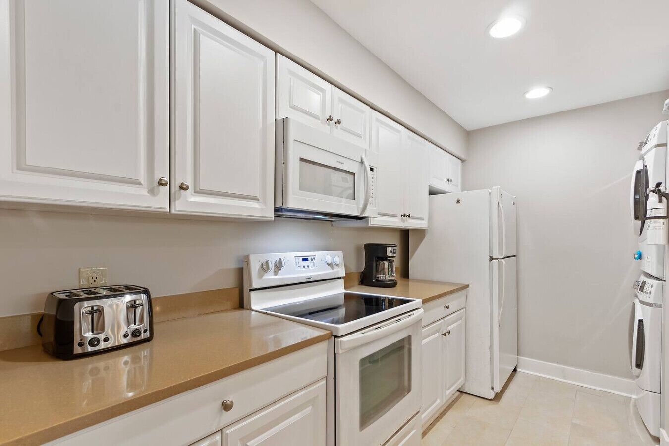 Una cocina moderna con armarios blancos, microondas, horno, tostadora y refrigerador.