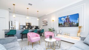 A modern living room with grey sofas, a coffee table, and a kitchen in the background. - Magical Stay Mickey and Harry Potter Rooms (Kissimmee)