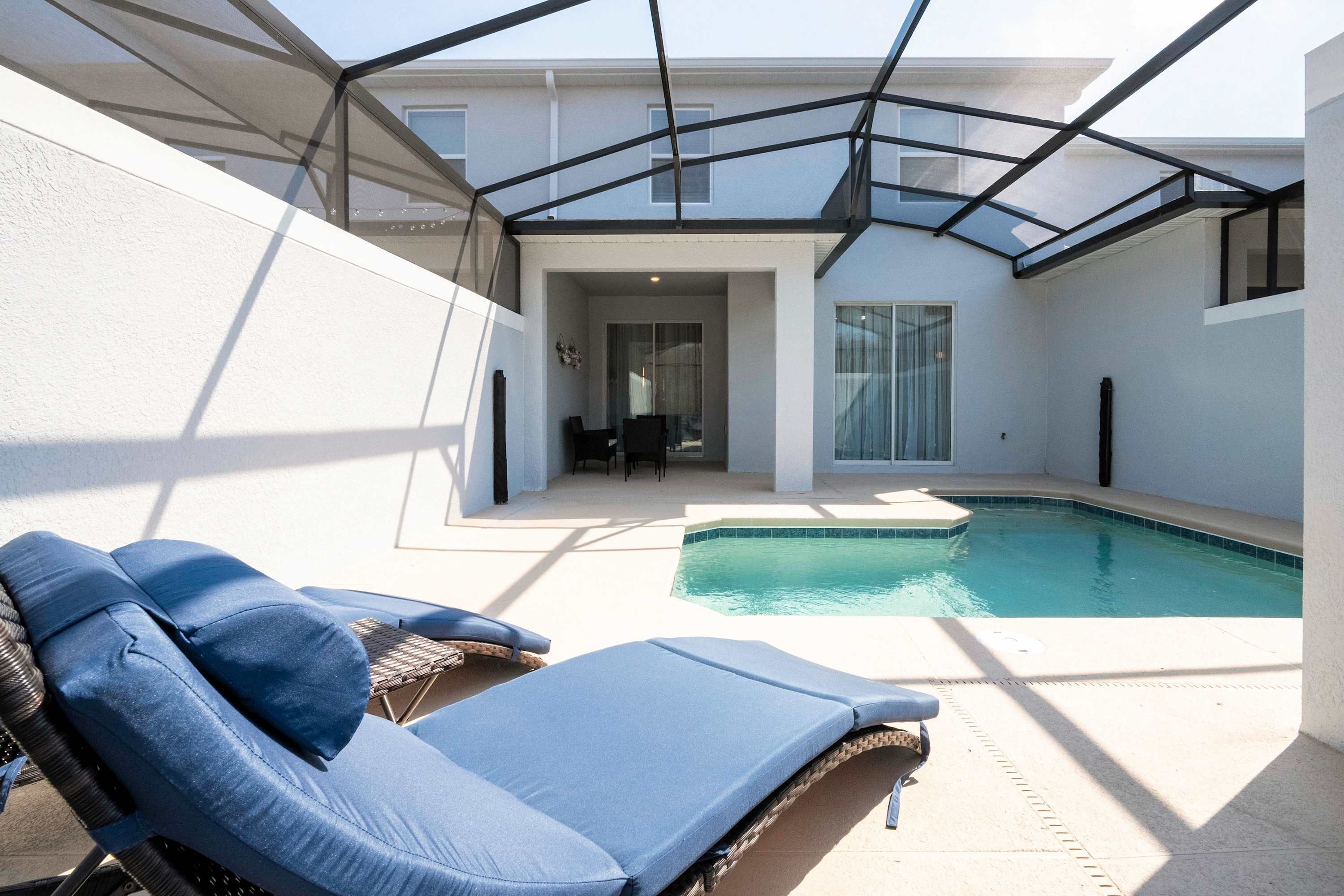 A poolside area with lounge chairs, a glass-enclosed patio, and a clear view of the pool.