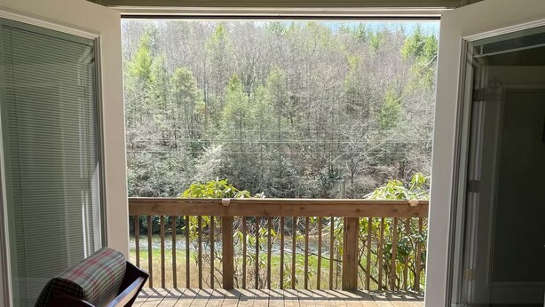 Una habitación con vistas a una terraza de madera y un bosque.