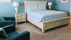 A bedroom with a bed, nightstands, a chair, and two lamps. - SPECIAL PRICES FOR SEPT!  Beachfront Retreat! Monthly specials you can't believe (Panama City Beach)