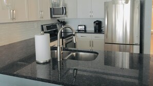 A modern kitchen with stainless steel appliances, a black countertop, and pendant lights. - SPECIAL PRICES FOR SEPT!  Beachfront Retreat! Monthly specials you can't believe (Panama City Beach)