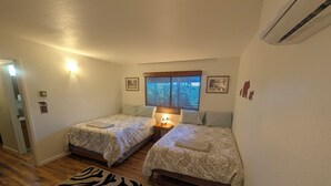 Ein Schlafzimmer mit zwei Betten, einem zebra-muster Teppich, einem Fenster mit Jalousien und Wandbildern.
