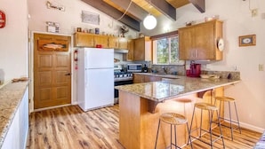 Eine Küche mit Holzschränken, einem weißen Kühlschrank, einem Herd und einer Arbeitsplatte aus Granit.