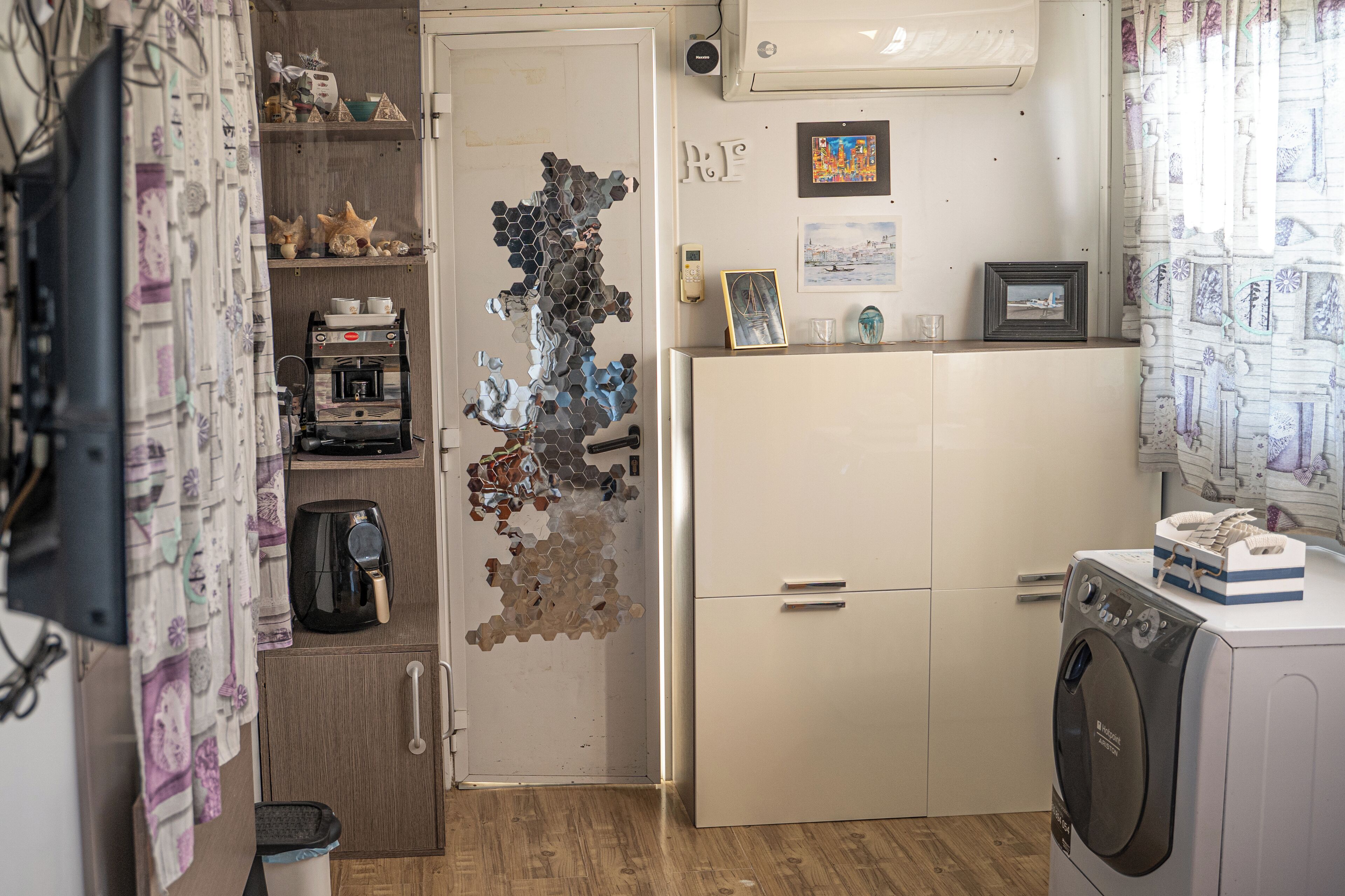 A compact kitchen with a coffee machine, a washing machine, and a refrigerator.
