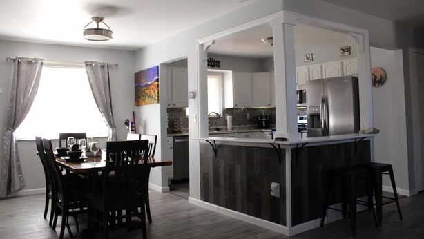 A modern kitchen with a central island, white cabinetry, and stainless steel appliances.