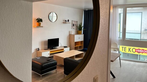 Una sala de estar moderna con televisor, sofá, mesa de centro y comedor con silla y mesa.